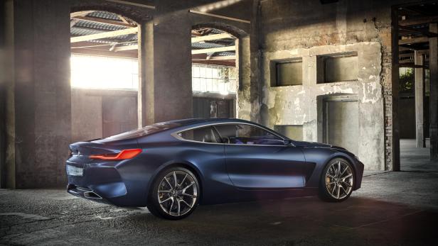 Ein blauer BMW der 8er-Reihe steht in einer alten Lagerhalle.
