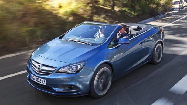Ein blaues Opel Cabriolet fährt auf einer Landstraße.