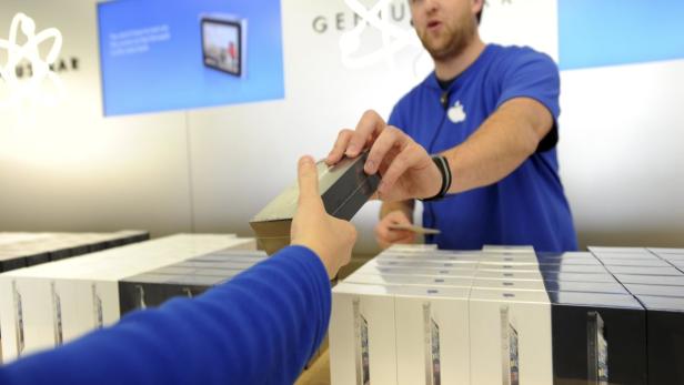 Ein Apple-Mitarbeiter übergibt einem Kunden eine iPhone-Verpackung.