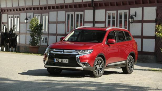Ein roter Mitsubishi Outlander steht vor einem Fachwerkhaus.