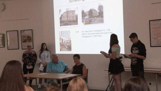 Drei Schülerinnen und ein Schüler präsentieren PowerPoint-Folien über das Projekt - für die Mitschüler_innen und Gäste