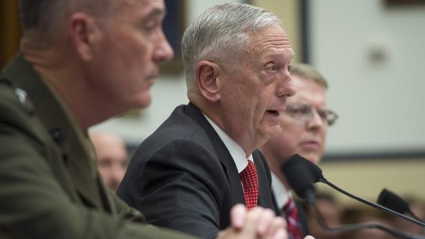 James Mattis spricht vor einem Mikrofon, flankiert von anderen Personen.