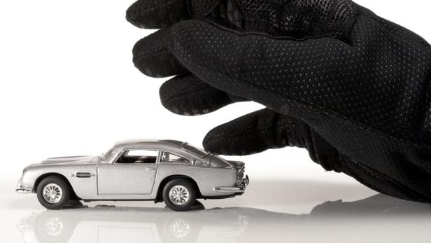 Modellauto und eine Hand in einem Handschuh.