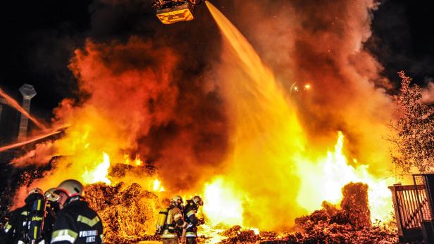 Feuerwehrleute bekämpfen einen Großbrand mit Wasserwerfern aus der Luft und vom Boden aus.