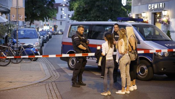 Ein bewaffneter Polizist spricht mit einer Gruppe junger Frauen vor einem Polizeiwagen.
