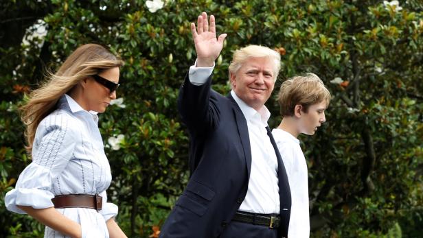 Donald Trump geht mit Melania und Barron Trump durch den Garten und winkt.