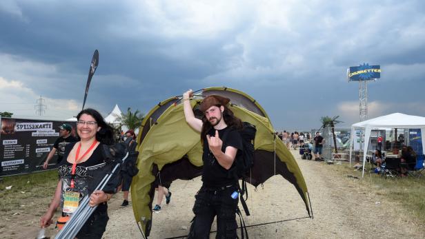 Ein Mann im Piratenhut hält ein Zelt hoch, während eine Frau mit Zeltstangen vorbeigeht.