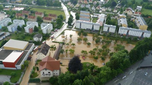Überschwemmung in einem Wohngebiet mit Wohnhäusern und Bäumen im Wasser.
