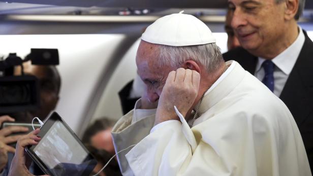 Der Papst sieht sich im Flugzeug eine Videobotschaft an
