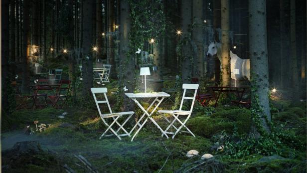 Eine Szene in einem Wald mit Tischen, Stühlen, Lampen und einer Pferdeattrappe.