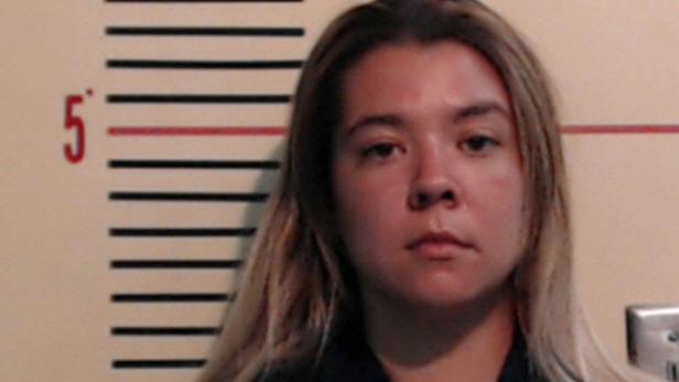 Eine Frau mit blonden Haaren vor einer Wand mit einer Größenmarkierung.