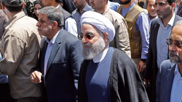 Der iranische Präsident Hassan Rohani mit Turban und Sonnenbrille inmitten einer Menschenmenge.