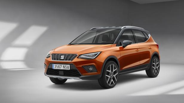 Ein orangefarbener Seat Arona vor einem grauen Hintergrund.