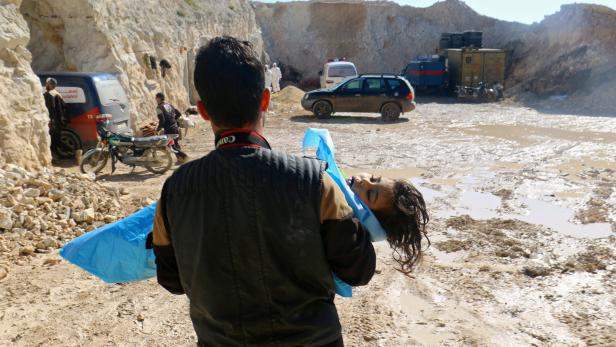 Ein Mann trägt ein totes Kind nach dem Giftgas-Angriff im April, der dem syrischen Regime zugeschrieben wird.