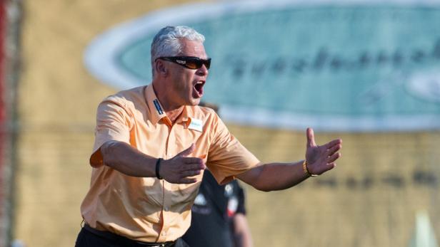 Ein Trainer mit Sonnenbrille gestikuliert und schreit Anweisungen.