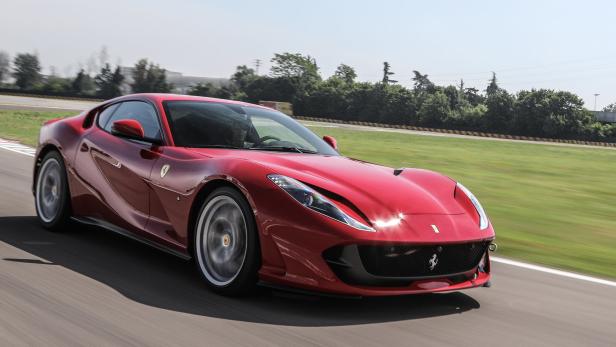 Ein roter Ferrari fährt auf einer Rennstrecke.
