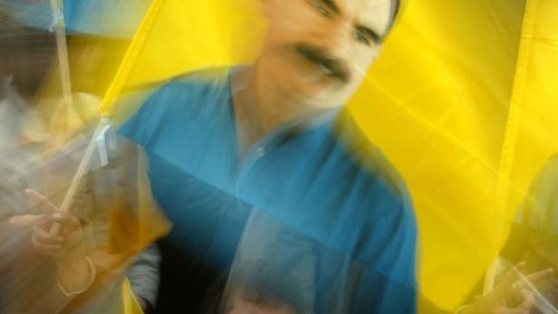 A Kurdish man makes a victory sign with his hand as he holds a portrait of Kurdish separatist leader Abdullah Ocalan, during a demonstration February 14, 2004 in Strasbourg, France. More than 15,000 Kurdish demonstrators protested in Strasbourg to ask for the freeing of their leader Ocalan who, captured on February 15, 1999, is now serving a life sentence in jail in Turkey. REUTERS/Vincent Kessler