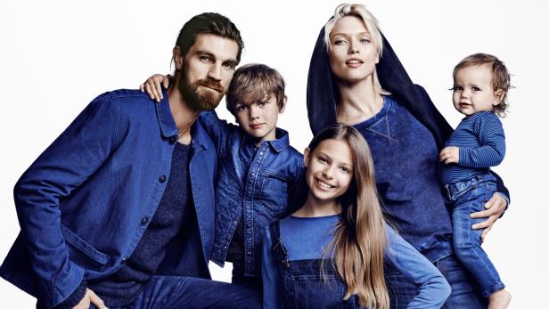 Eine Familie, gekleidet in verschiedene Blautöne, posiert für ein Foto.
