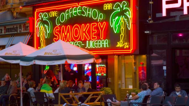 Gäste sitzen vor dem „Smokey“ Café, Coffeeshop, Bar und genießen Getränke.