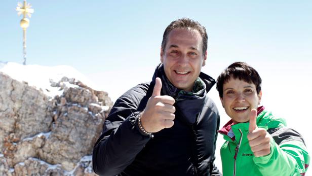 Zwei Personen geben auf der Zugspitze mit Gipfelkreuz den Daumen nach oben.