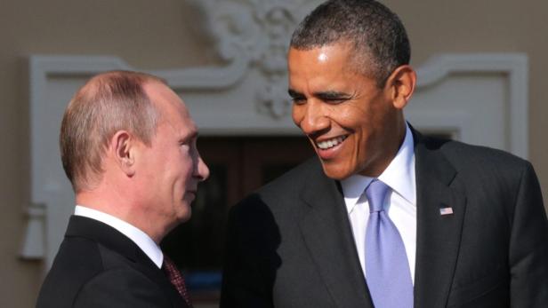 Barack Obama und Wladimir Putin stehen einander gegenüber und lächeln.