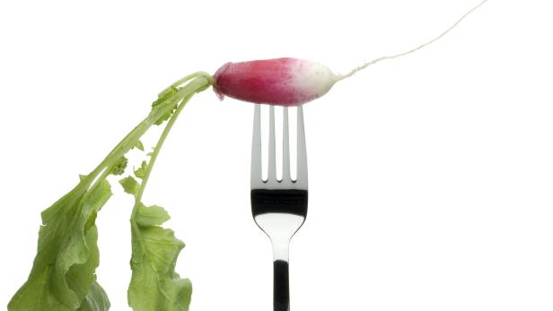 A radish on a fork, on a white background