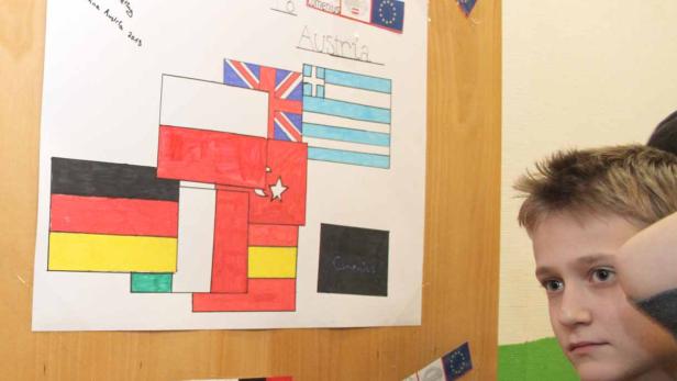 Ein Junge betrachtet ein Plakat mit Flaggen und der Aufschrift „Welcome to Austria“.