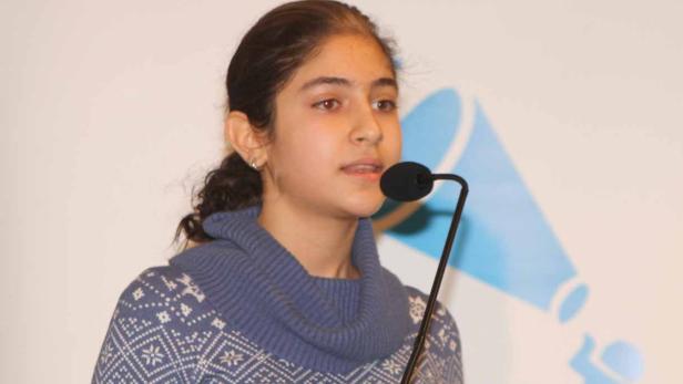 Ein junges Mädchen spricht bei einer Veranstaltung zum Thema „Wirtschaft für Integration“.