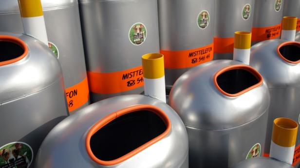 Mehrere silberne Hundekotbehälter mit der Aufschrift „Misttelefon“ stehen nebeneinander.