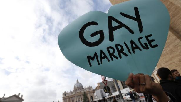 Eine Person hält ein Schild mit der Aufschrift „Gay Marriage“ vor dem Petersdom.