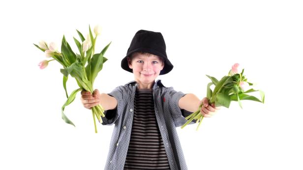 Ein Junge mit Hut präsentiert zwei Sträuße Tulpen.