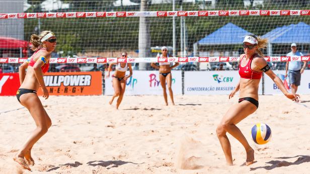 Zwei Beachvolleyballteams spielen am Strand gegeneinander.