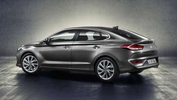 Ein grauer Hyundai i30 Fastback steht vor einer grauen Wand.