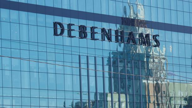 Die Fassade eines Debenhams-Gebäudes spiegelt ein anderes Gebäude wider.