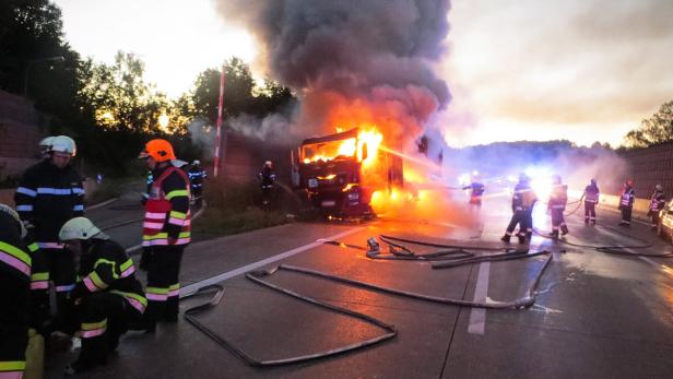 Ein brennender Lastwagen auf einer Autobahn wird von Feuerwehrleuten gelöscht.
