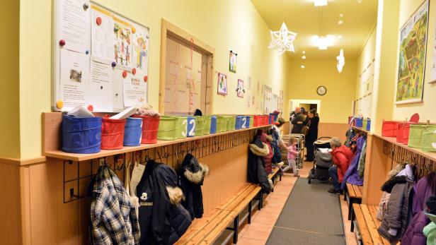 Ein Flur in einer Kindertagesstätte mit Garderoben und spielenden Kindern.