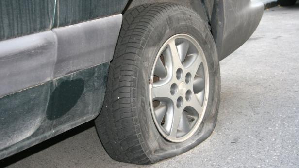Ein platter Reifen an einem dunklen Auto.