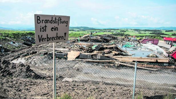Ein Schild mit der Aufschrift &quot;Brandstiftung ist ein Verbrechen&quot; vor den Trümmern des niedergebrannten Asylquartiers in Altenfelden