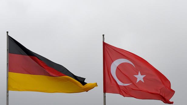 Die deutsche und die türkische Flagge wehen nebeneinander vor einem grauen Himmel.