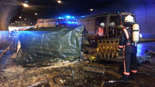 Feuerwehrleute arbeiten in einem Tunnel nach einem Unfall, der mit einer Plane abgedeckt ist.