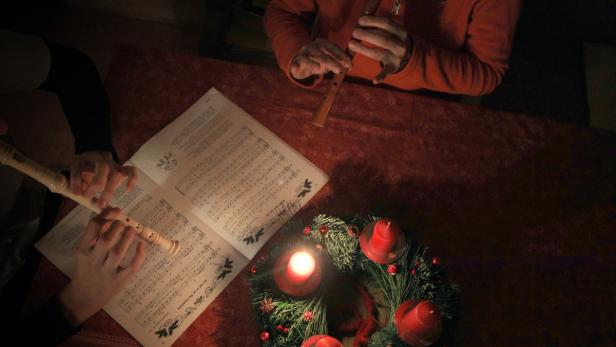 Zwei Personen spielen Blockflöte neben einem Adventskranz.
