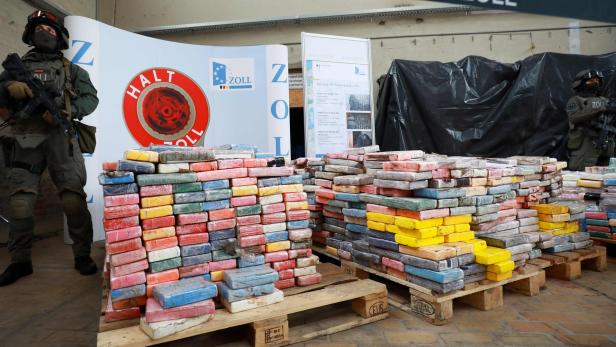 Zollbeamte präsentieren sichergestellte, in farbiges Plastik verpackte Kokainpakete.