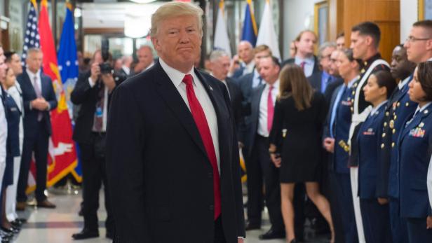 Donald Trump steht vor einer Gruppe von Militärangehörigen und anderen Personen.