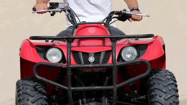 Ein rotes Yamaha-Quad steht auf sandigem Untergrund.