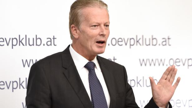 Ein Mann im Anzug gestikuliert vor einem Hintergrund mit der Aufschrift „oevpklub.at“.