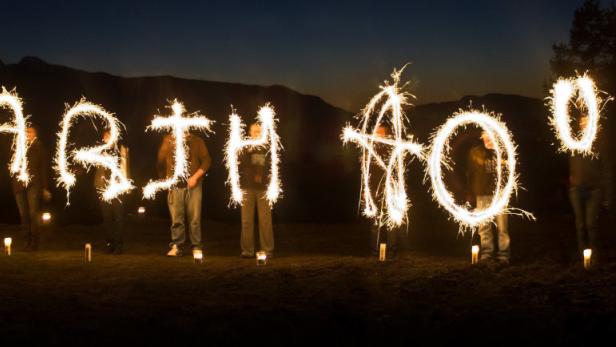 Mehrere Personen schreiben mit Wunderkerzen den Schriftzug „Earth Hour“ in den Nachthimmel.