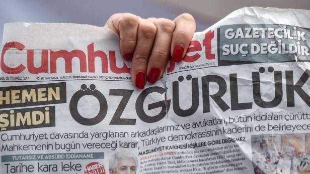 Eine Frau hält eine Zeitung mit der Schlagzeilge &quot;Freiheit&quot; in die Höhe.