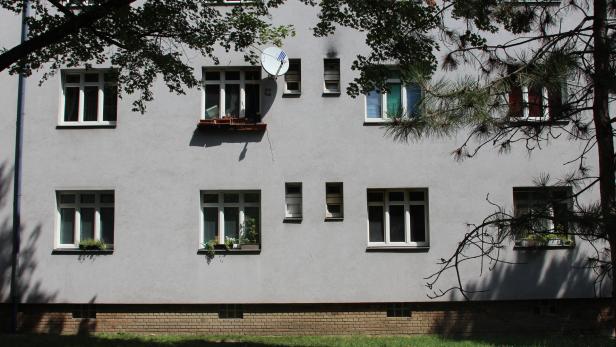 Die Fassade eines Mehrfamilienhauses mit mehreren Fenstern und einer Satellitenschüssel.