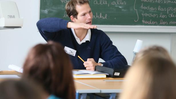 Ein Lehrer erklärt den Schülern den Artikel vor einer Tafel.