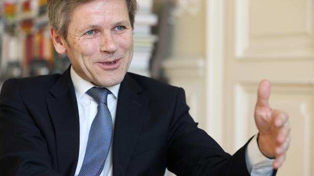 Ein Mann im Anzug gestikuliert mit der Hand.